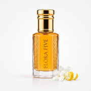 Ajmal Aurum inspired attar for women — alcohol-free perfume oil by Flora Five: golden-yellow oil with white jasmine and a lemon peel curl on white