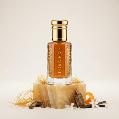 Caramel Oud by Flora Five — gold-capped bottle of orange-amber oil on an onyx block with spun caramel, oud chips and orange peel – 3, 6 and 12 ml