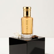 Carolina Herrera Good Girl inspired attar for women — alcohol-free attar oil by Flora Five: golden oil on a black plinth with a tuberose and coffee beans
