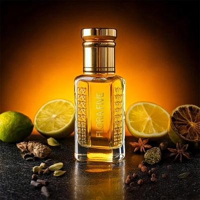 Dior Sauvage inspired attar for men by Flora Five — alcohol-free perfume oil: gold-capped bottle of golden oil on dark stone in orange light with limes, lemon slices and star anise – 3, 6 and 12 ml