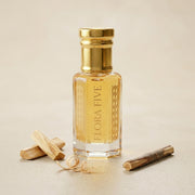 Sandalwood Eco Attar, unisex — alcohol-free attar oil by Flora Five: pale gold oil on cream with sandalwood sticks, a shaving curl and a twig