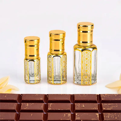 Choco Musk Attar by Flora Five — three empty gold-capped bottles of different heights in front of a chocolate bar – 3, 6 and 12 ml