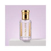 Iris Violet Attar for women — alcohol-free perfume oil by Flora Five: pale lilac oil in a gold-capped bottle on a white block against a lilac backdrop