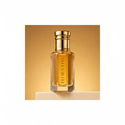 Kasturi Attar, unisex — alcohol-free attar oil by Flora Five: amber oil in a gold-capped bottle on a cream plinth against a honey-gold backdrop