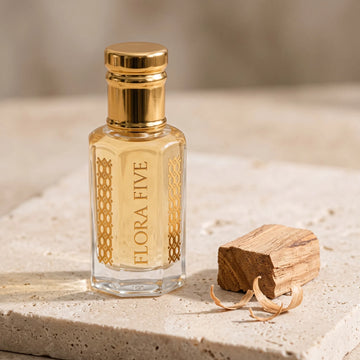Sandalwood Attar, unisex — alcohol-free attar oil by Flora Five: pale golden oil on travertine with a sandalwood block and curled shavings