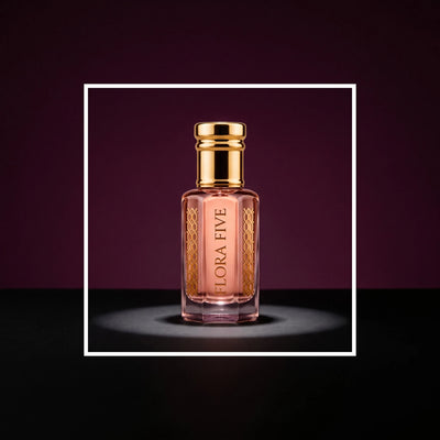 Wesal Attar, unisex — alcohol-free attar oil by Flora Five: rose-pink oil in a spotlight on a plum backdrop inside a white frame