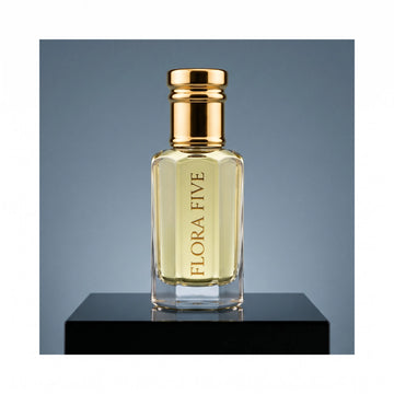 YSL Y inspired attar for men — alcohol-free perfume oil by Flora Five: pale gold oil on a black plinth against a steel-blue backdrop