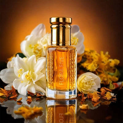Baccarat Rouge 540 Attar by Flora Five – alcohol-free amber floral oil perfume with luxurious notes of saffron, jasmine, and amberwood in an elegant golden bottle surrounded by white and yellow blossoms
