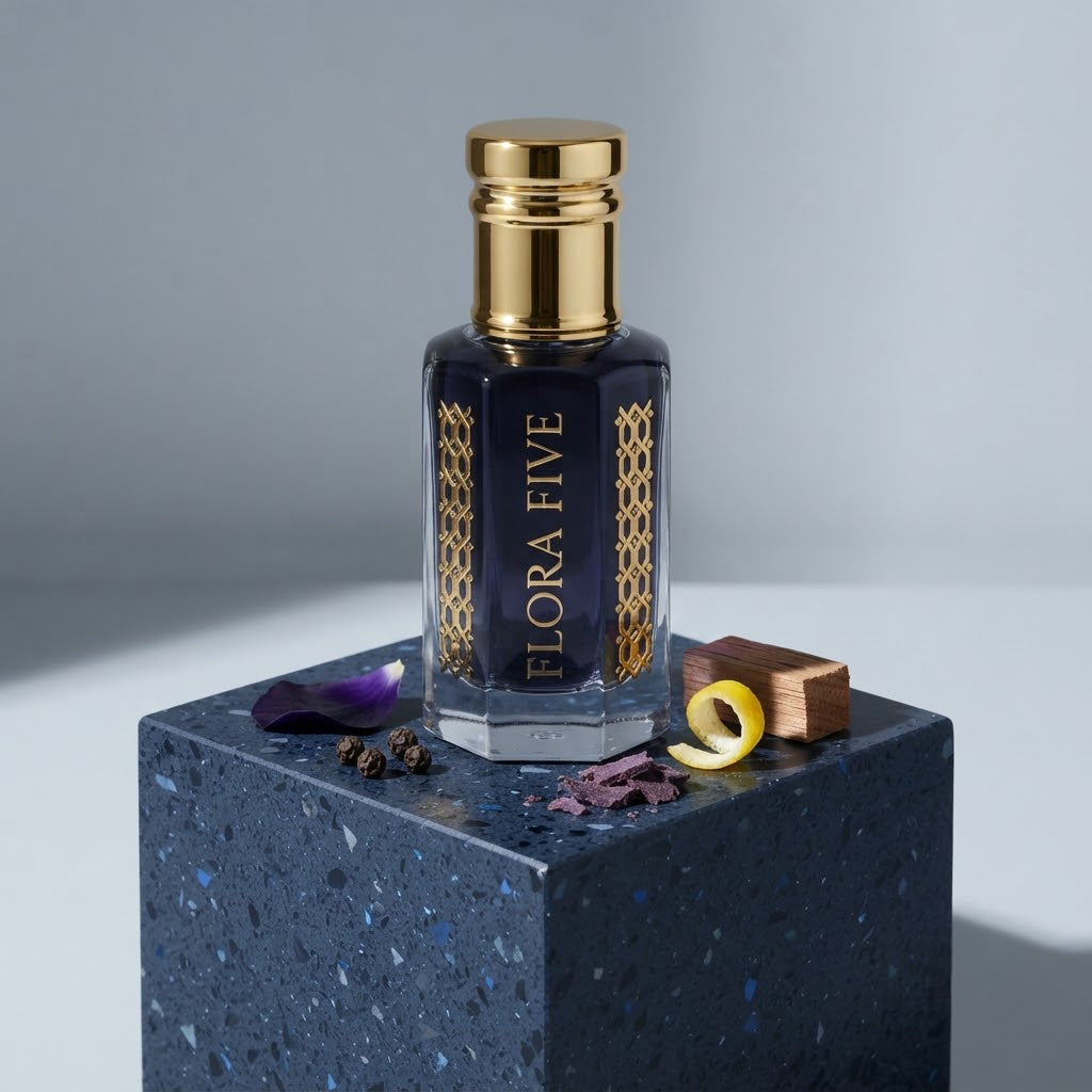 Blue Noir Attar by Flora Five — gold-capped bottle of deep navy oil on a blue stone block with violets, lemon peel and a cedar block – 3, 6 and 12 ml