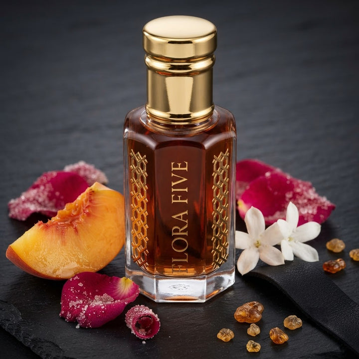 Burberry Black Inspired Attar by Flora Five — gold-capped bottle of deep red-amber oil on dark slate with a peach slice, rose petals and jasmine – 3, 6 and 12 ml
