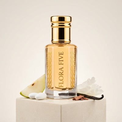 Burberry Brit inspired attar for women by Flora Five — alcohol-free perfume oil: gold-capped bottle of golden yellow oil on a white block with a pear slice, white flowers and a vanilla pod – 3, 6 and 12 ml