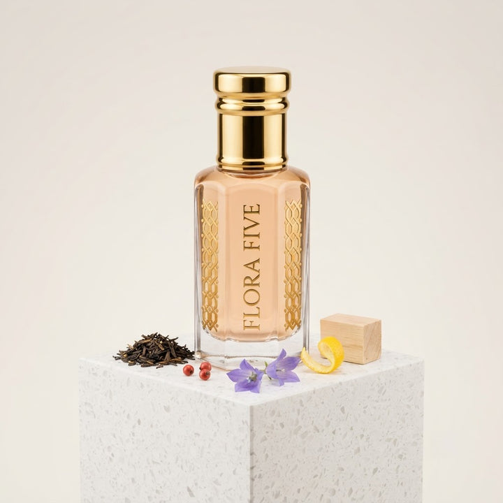 Burberry The Beat for Women Inspired Attar by Flora Five — gold-capped bottle of pale peach oil on a white stone block with tea leaves, bellflowers and pink pepper – 3, 6 and 12 ml