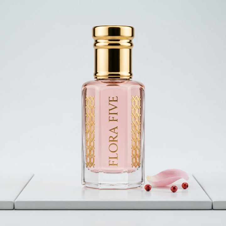Byredo Rose of No Man's Land Inspired Attar by Flora Five — gold-capped bottle of pale pink oil on a white tile with a rose petal and pink peppercorns – 3, 6 and 12 ml