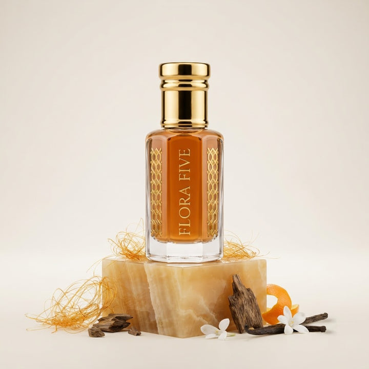 Caramel Oud by Flora Five — gold-capped bottle of orange-amber oil on an onyx block with spun caramel, oud chips and orange peel – 3, 6 and 12 ml