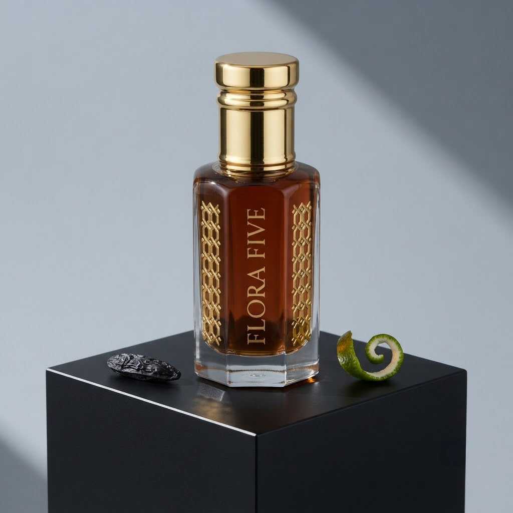 Carolina Herrera Bad Boy Inspired Attar by Flora Five — gold-capped bottle of deep red-brown oil on a black plinth with a tonka bean and lime peel – 3, 6 and 12 ml