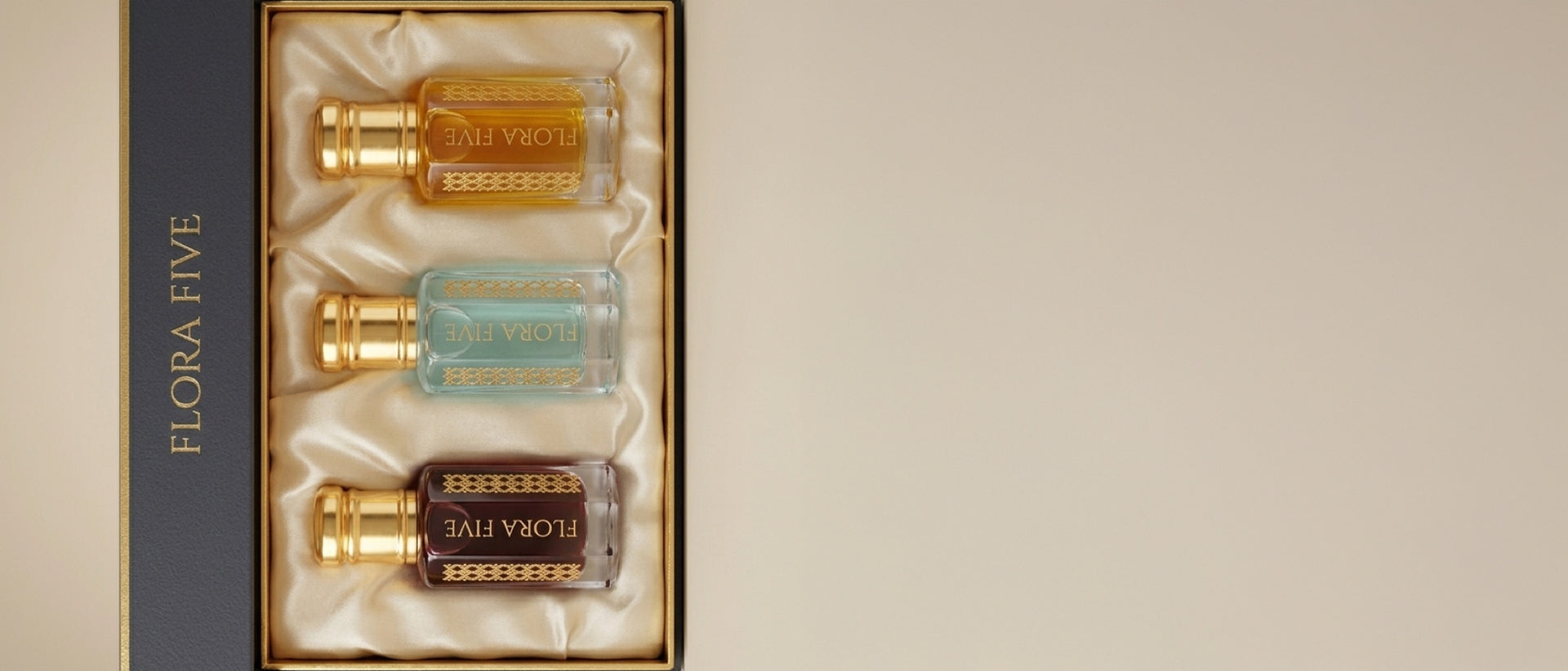 Flora Five Attar Trio gift box — maroon, light blue, amber-gold attars with FLORA FIVE side panel, on cream backdrop