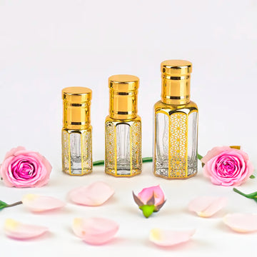 Musk Rose Attar for women — alcohol-free perfume oil by Flora Five: three empty gold-capped bottles with pink roses, a rosebud and petals