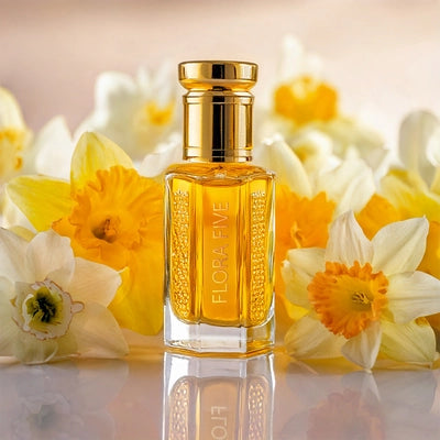 Nectar De Nargis Attar by Flora Five – handcrafted oil-based perfume with rich floral notes of narcissus; long-lasting and elegant in a golden bottle surrounded by fresh nargis flowers