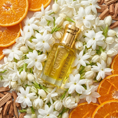 Puberty Attar by Flora Five in a luxury glass perfume oil bottle surrounded by fresh jasmine flowers, orange slices, and warm woody accents