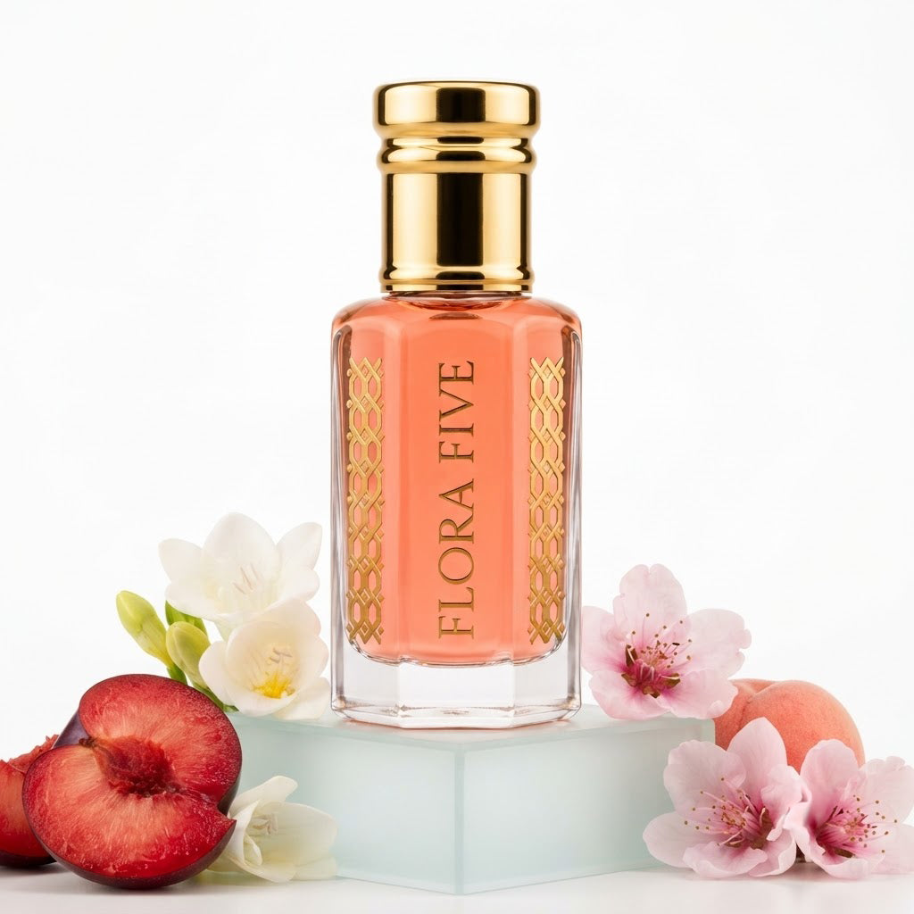 Victoria's Secret Pure Seduction Inspired Attar by Flora Five — gold-capped bottle of coral-red oil on a frosted block with blood plums, freesia and pink blossoms – 3, 6 and 12 ml