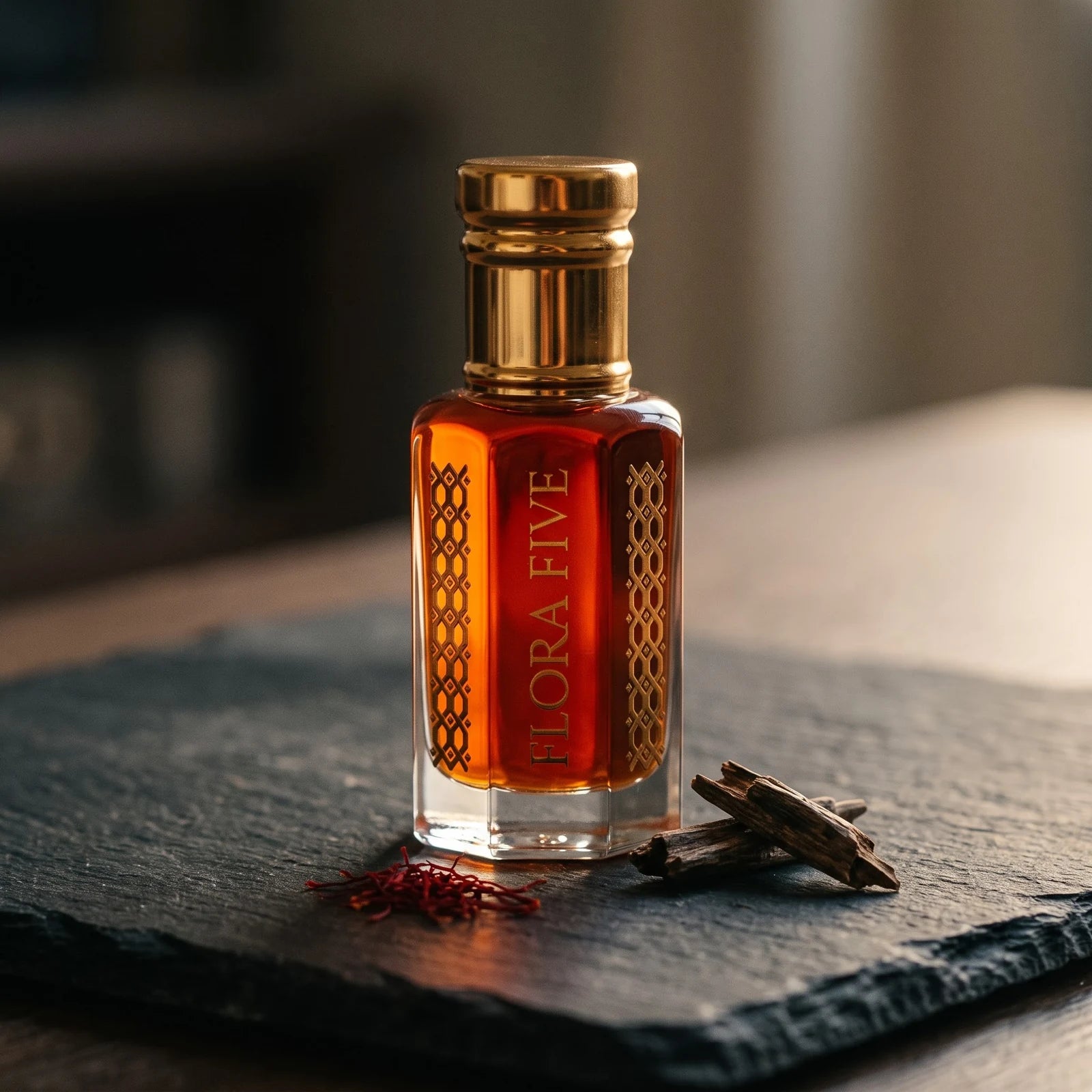Aatish Oud by Flora Five — amber oud oil bottle on dark slate with agarwood chips and saffron threads