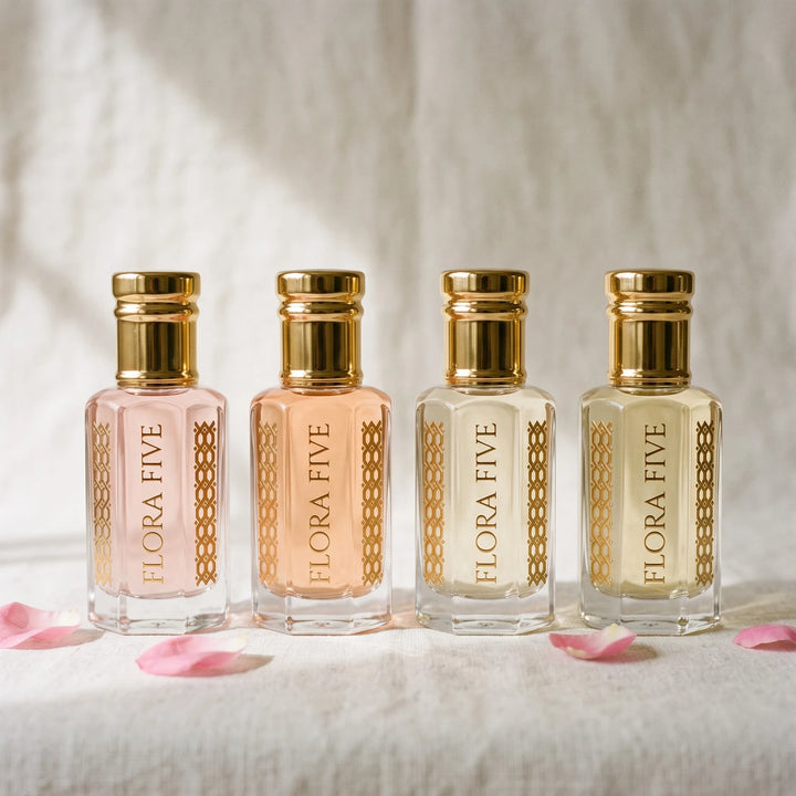 Bloom & Musk Combo unisex — four alcohol-free attar oils by Flora Five in blush, peach, ivory and pale gold bottles on ivory linen with rose petals