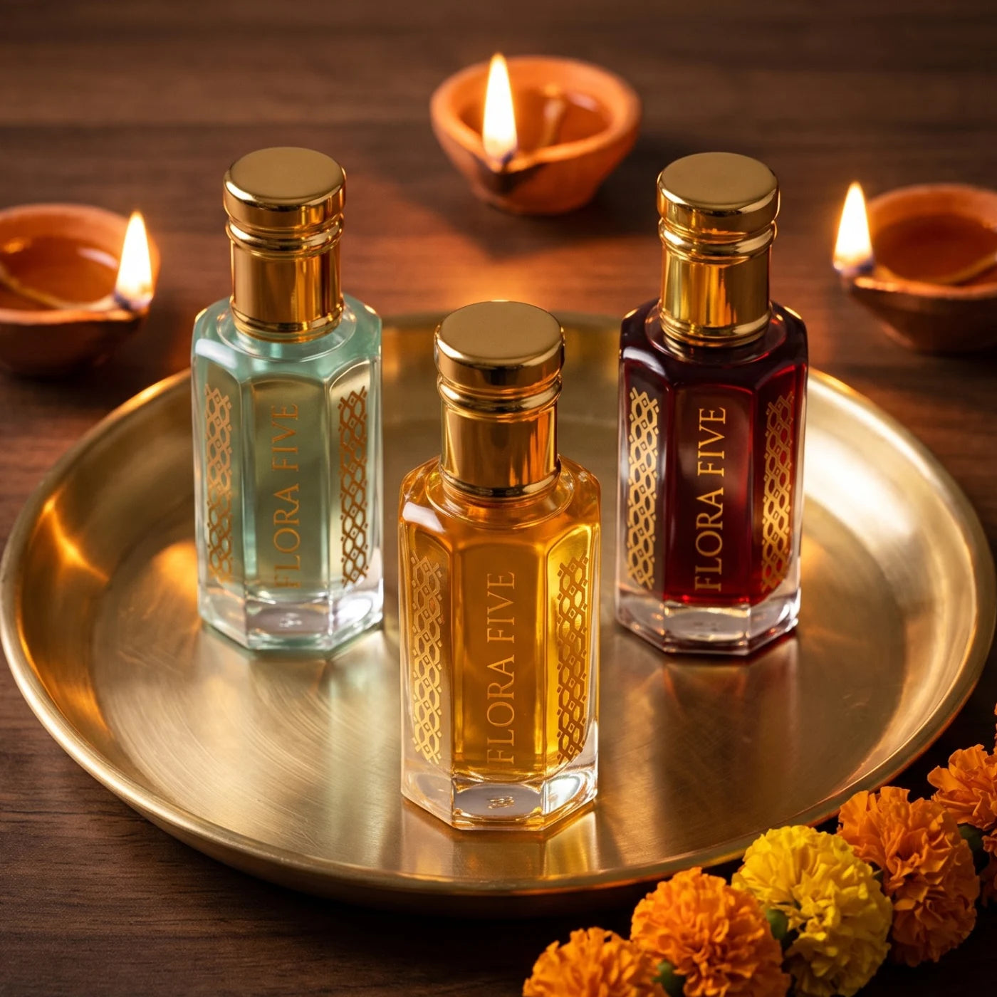 Build Your Trio by Flora Five — Diwali gift setting with aqua, golden and garnet attar bottles on a brass thali with lit diyas and marigolds