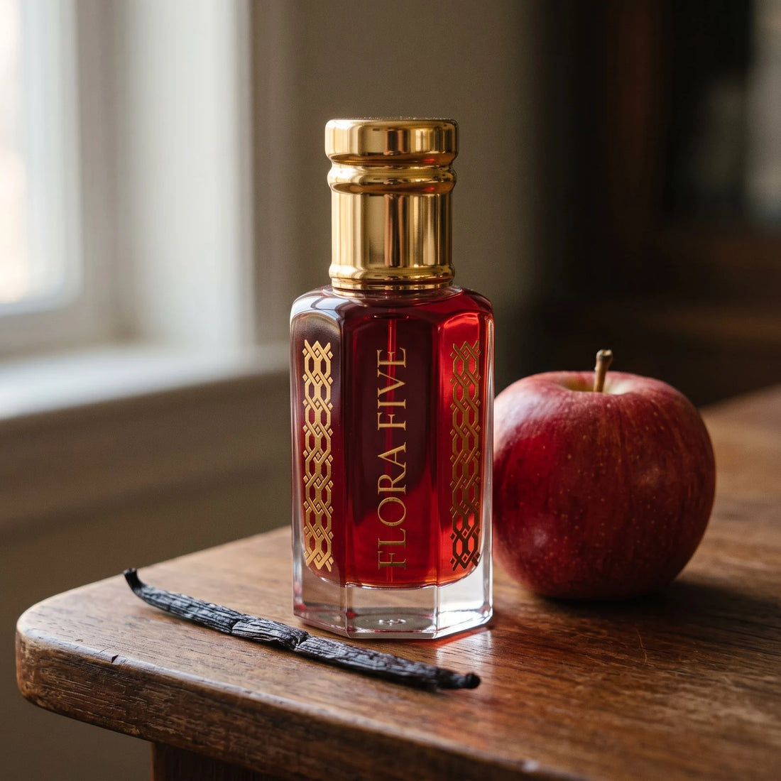 Dunhill Red inspired attar by Flora Five: ruby red oil bottle on teak with a red apple and a vanilla pod