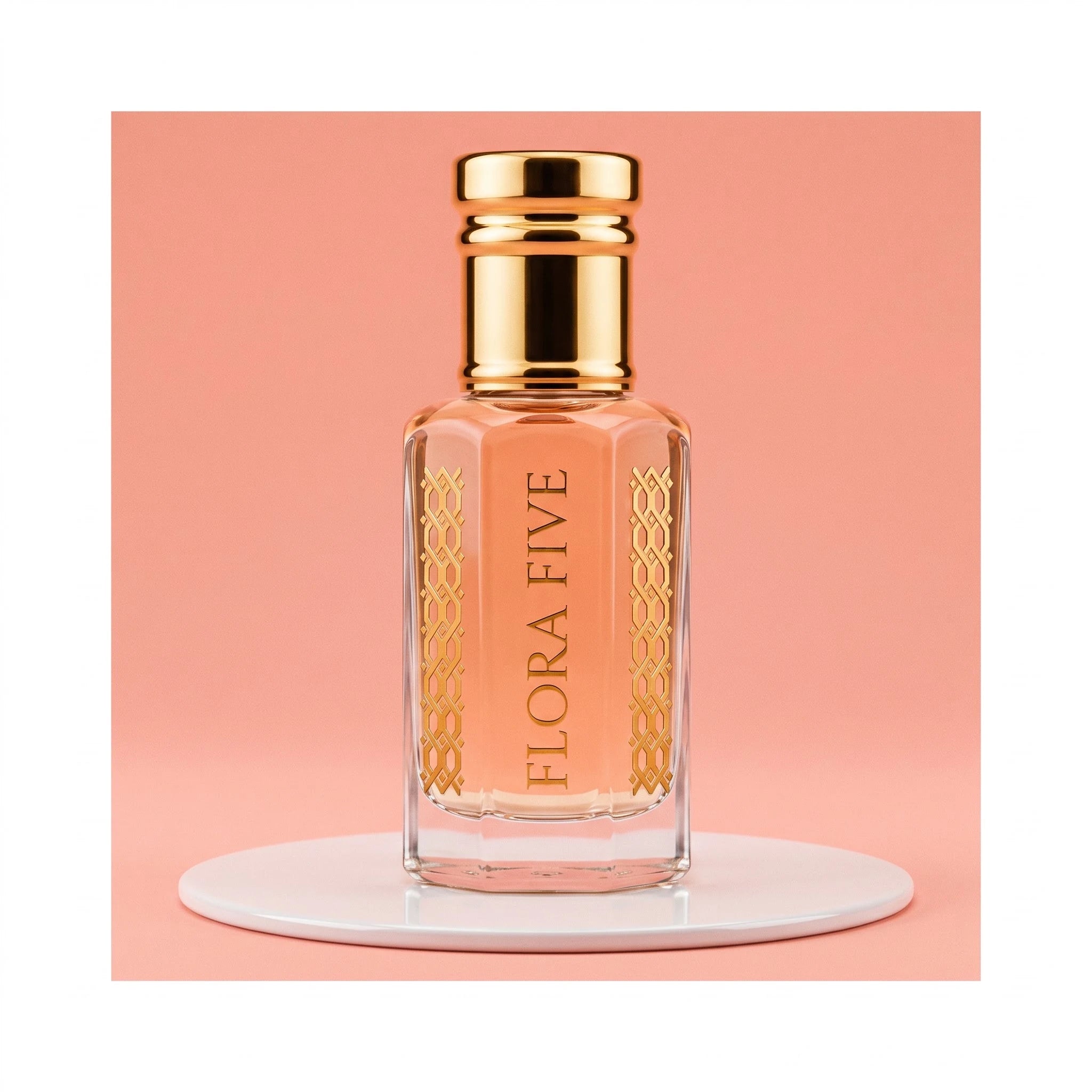 Escada Kiss Land inspired attar for women — alcohol-free perfume oil by Flora Five: peach oil in a gold-capped bottle on a white plinth against coral pink