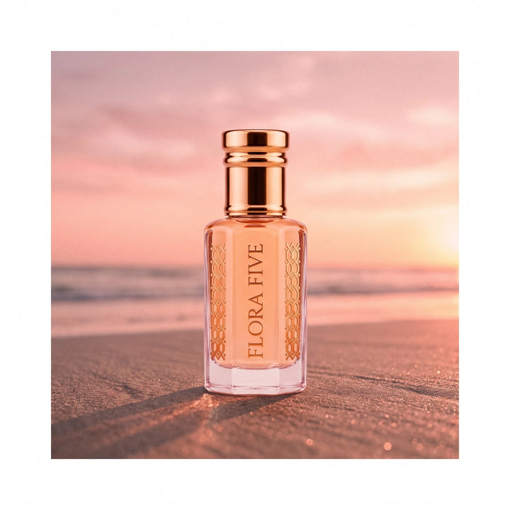Escada Kiss Land inspired attar by Flora Five — peach oil bottle on wet sand at a pink beach sunset