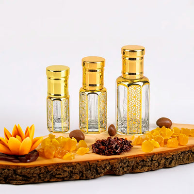 Golden Sand Oud by Flora Five — three empty gold-capped bottles of different heights on a wooden board with resin, amber pieces and dried fruit – 3, 6 and 12 ml
