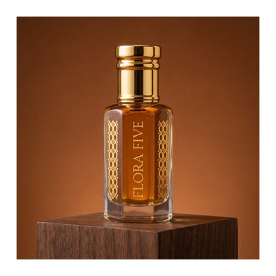 Khulasatal Oud, unisex — alcohol-free oud oil (oudh) by Flora Five: deep amber oil in a gold-capped bottle on walnut against a cognac backdrop