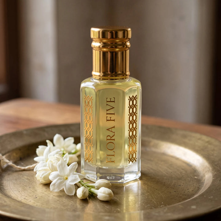 Mogra Attar, unisex — alcohol-free perfume oil by Flora Five: pale yellow oil on a brass plate with a strand of mogra jasmine flowers