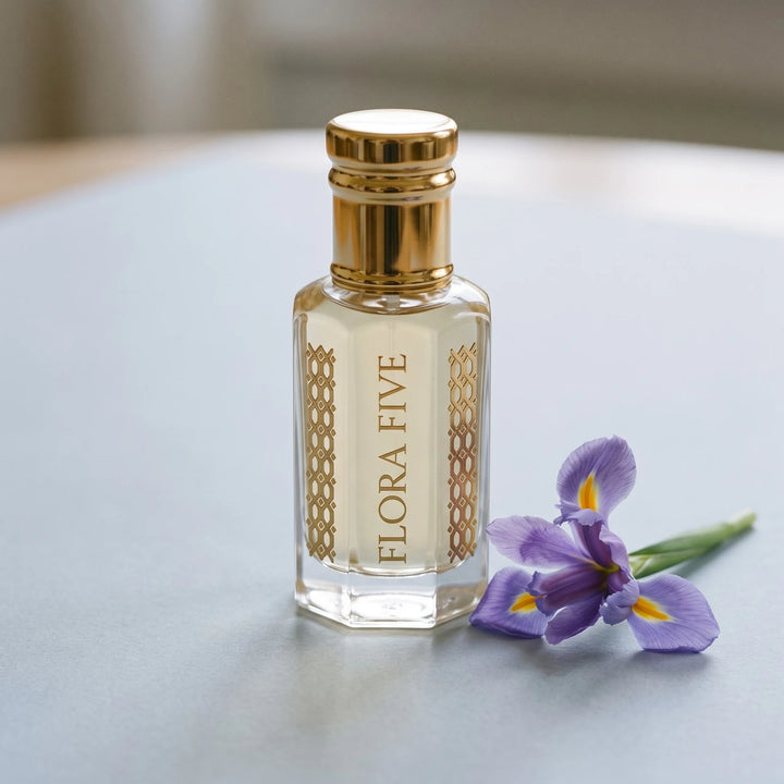 Prada L'Homme inspired attar by Flora Five: pale gold oil bottle on grey-blue paper with an iris flower
