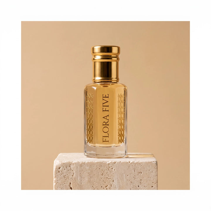 Sandal Aura Attar, unisex — alcohol-free attar oil by Flora Five: pale golden oil in a gold-capped bottle on a travertine block, sand-beige backdrop