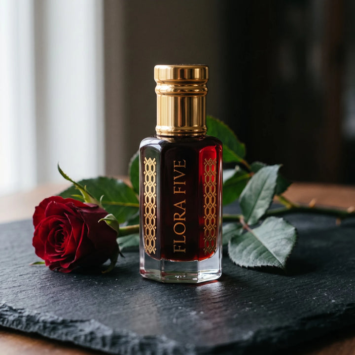 Tom Ford Noir de Noir inspired attar by Flora Five: dark garnet oil bottle on black slate with a dark red rose