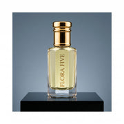 YSL Y inspired attar for men — alcohol-free perfume oil by Flora Five: pale gold oil on a black plinth against a steel-blue backdrop